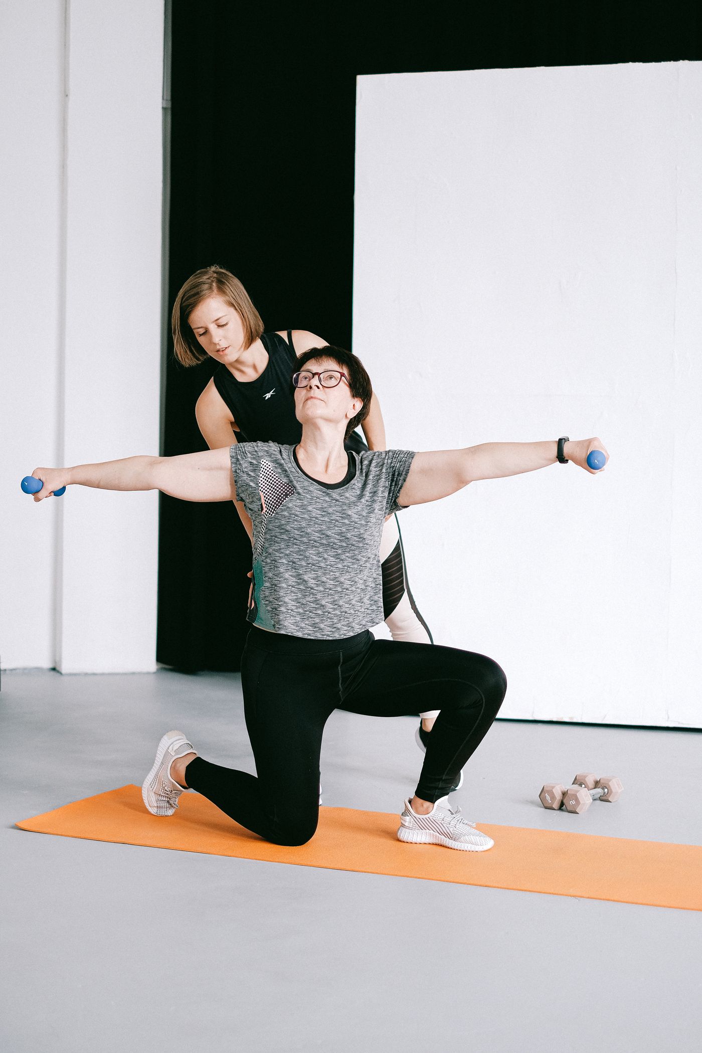 A coach supporting a woman during a strength movement