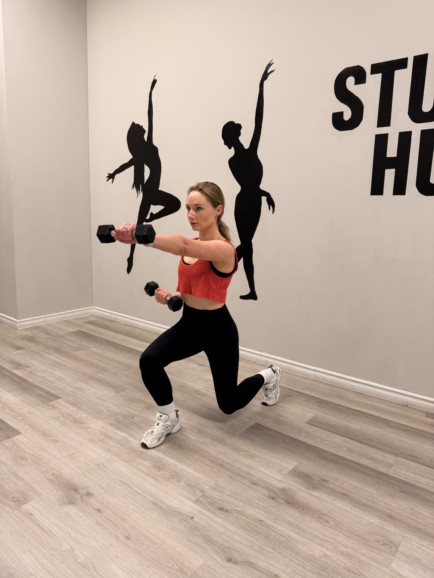 Woman performing a strength lunge with dumbbells in the studio